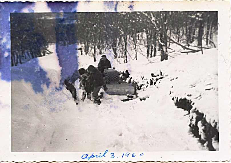1960 April 3 - Linda and John helping Sharon in the snow, patient father on tractor, making our way up our mountain road